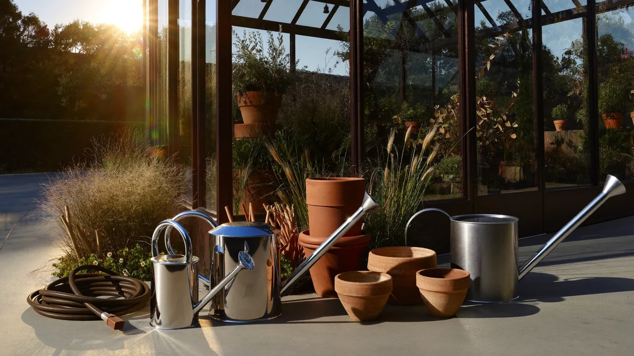 Illustrative watering cans, clay pots and a coiled hose beside a glasshouse door
